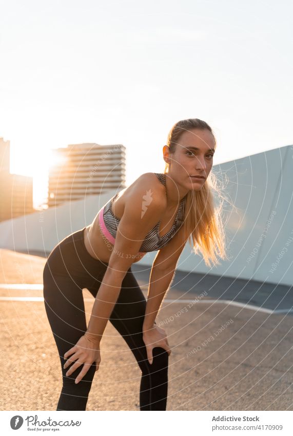 Sportlerin ruht sich nach dem Training in der Sonne auf dem Bürgersteig aus Athlet ruhen Straßenbelag Sportbekleidung passen Pause Wellness Gesunder Lebensstil