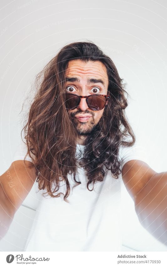 Hipster Mann mit lustigen überraschtes Gesicht Blick auf die Kamera Überraschung erstaunt lange Haare Vollbart Sonnenbrille Menschliches Gesicht expressiv