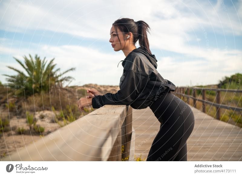 Sportliche Frau ruht sich nach dem Training auf der Strandpromenade aus sportlich passen ruhen sich[Akk] entspannen Fitness Kopfhörer Erholung Wiederherstellung