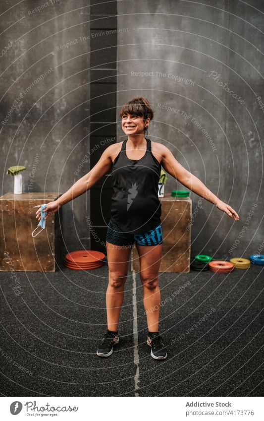 Lächelnde schwangere Sportlerin im Fitnessstudio Athlet Frau heiter Training Bauch Wellness passen Sportbekleidung modern Gesundheit Glück Vitalität Freude Dame