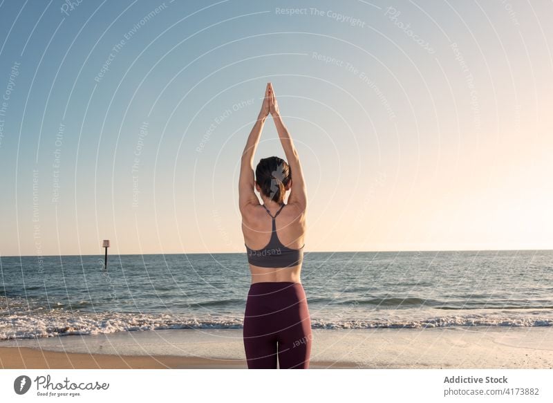 Schlanke Frau übt Yoga am Meeresufer MEER Strand üben Asana Berge u. Gebirge Pose stehen urdhva hastasana Gleichgewicht Windstille Harmonie Wellness Lifestyle