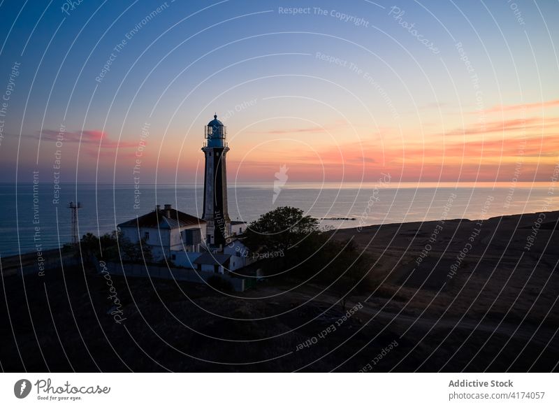 Einsamer Leuchtturm an der Küste des Meeres bei Sonnenuntergang Leuchtfeuer MEER navigieren Turm Himmel Dämmerung Landschaft erstaunlich Windstille Hügel