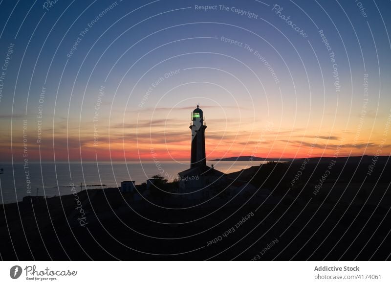 Einsamer Leuchtturm an der Küste des Meeres bei Sonnenuntergang Leuchtfeuer MEER navigieren Turm Himmel Dämmerung Landschaft erstaunlich Windstille Hügel