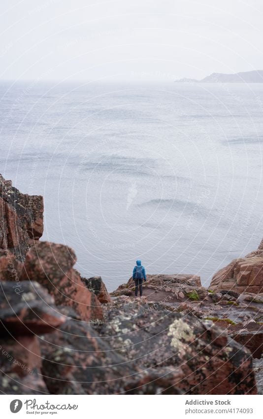 Unbekannter Reisender auf einem Hügel am Meer reisen Abenteuer Fernweh MEER Aussichtspunkt beobachten wolkig Herbst Entdecker Rucksack felsig Natur Tourismus