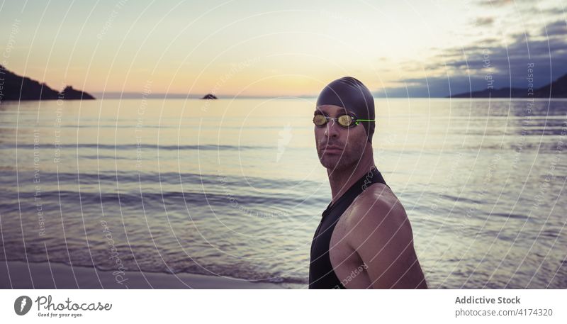 Männlicher Schwimmer mit Schwimmbrille am Meer Mann Schutzbrille MEER Meeresufer professionell Sportler Badeanzug Verschlussdeckel Strand männlich selbstbewusst