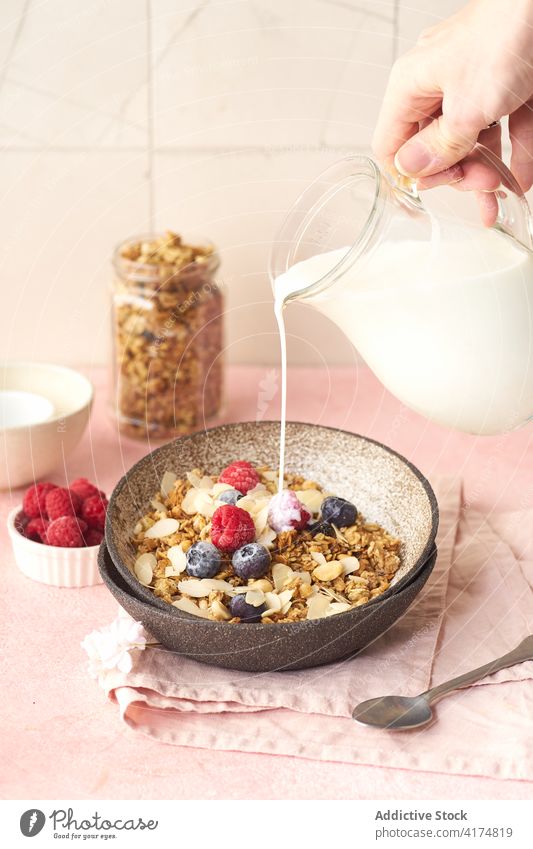 Frühstück mit Müsli, Beeren und Milch Lebensmittel Gesundheit Hand Gießen melken organisch Frucht Schalen & Schüsseln Korn Diät Schuppen Snack Joghurt frisch