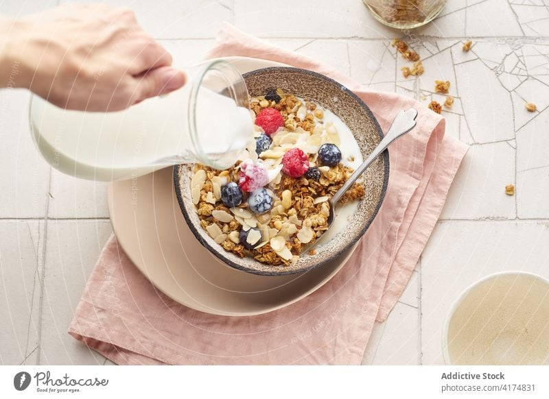 Frühstück mit Müsli, Beeren und Milch Lebensmittel Gesundheit Hand Gießen melken organisch Frucht Schalen & Schüsseln Korn Diät Schuppen Snack Joghurt frisch