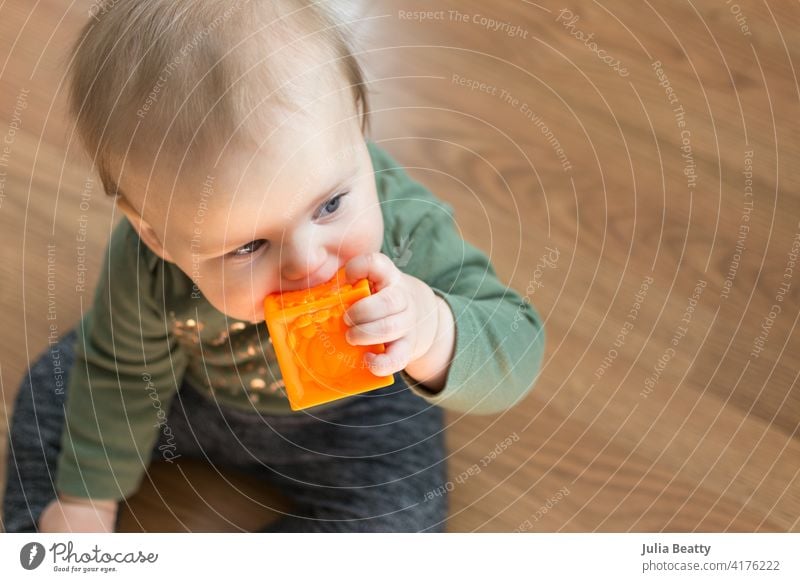 Kleines Kleinkind kaut auf weichem Blockspielzeug zur Linderung von Zahnungsschmerzen zahnend Biss Kauen Silikon Zähne Klotz Milchzähne sicher Sicherheit