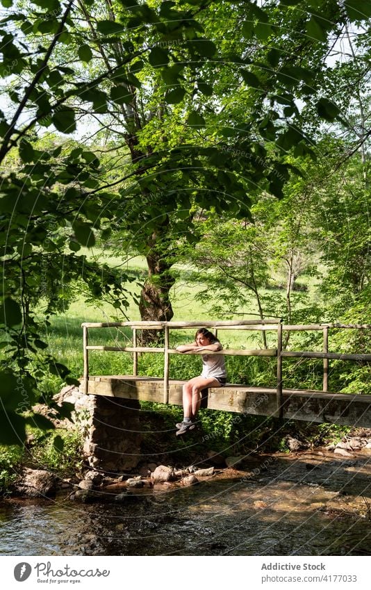 Frau entspannt auf Brücke im Wald Wälder Sommer sich[Akk] entspannen Fluss genießen sorgenfrei Natur friedlich ruhen Baum sitzen Freiheit Wasser Bach alt ruhig