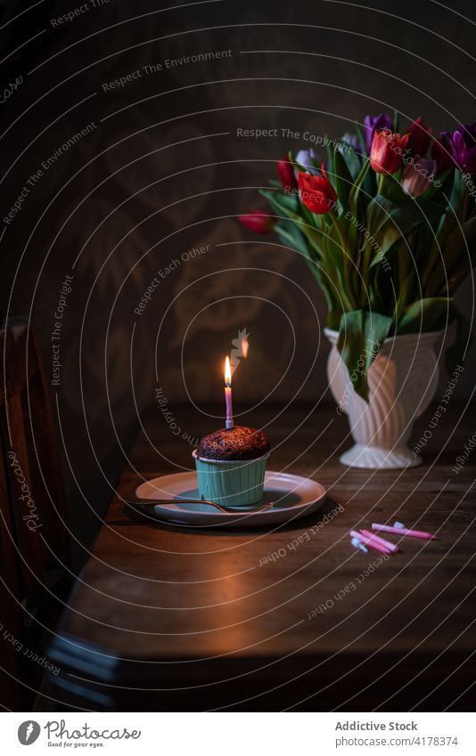 Schokoladen-Cupcake mit Kerze auf Tisch mit Blumen festlich Geburtstag Lebensmittel Gebäck süß Dessert feiern Feiertag Veranstaltung lecker Blumenstrauß