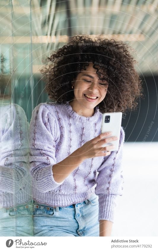 Schwarze Frau spricht in der Stadt mit einem Mobiltelefon Smartphone Großstadt Afro-Look Frisur Telefonanruf Straße urban ethnisch schwarz Afroamerikaner