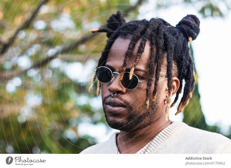 Moderner Typ mit Dreadlocks und Accessoires Mann trendy Stil Rastalocken Sonnenbrille cool modern Persönlichkeit Vorschein Streetstyle Kultur lässig Lifestyle