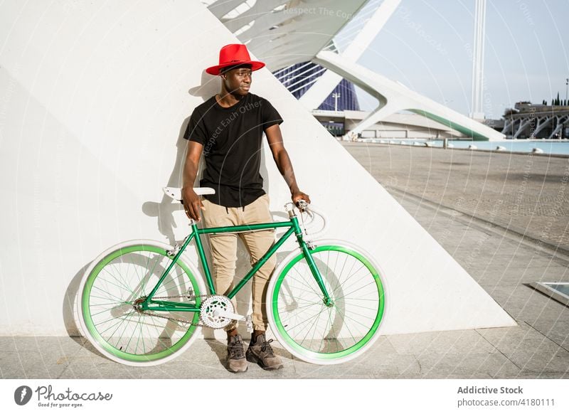 Stilvoller schwarzer Mann mit Fahrrad in der Stadt urban Großstadt jung modern trendy selbstbewusst männlich ethnisch Afroamerikaner Straße Vorschein Hipster