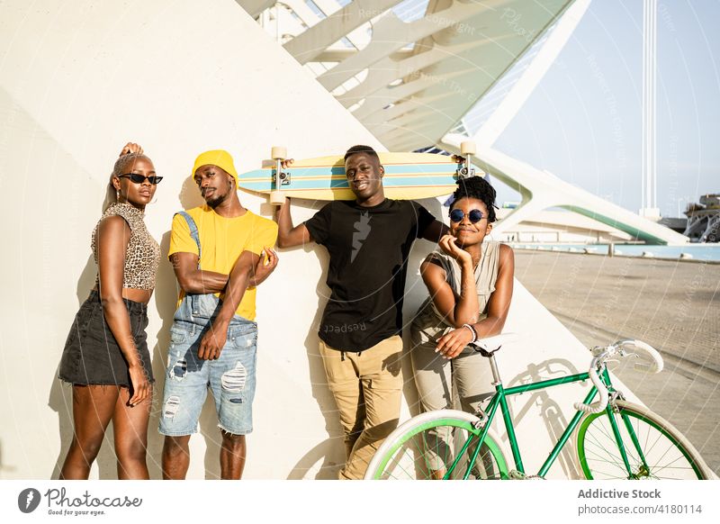 Gesellschaft von fröhlichen Freunden mit Fahrrad und Longboard in der Stadt Unternehmen Hipster Einheit cool Stil Generation Zusammensein ethnisch schwarz