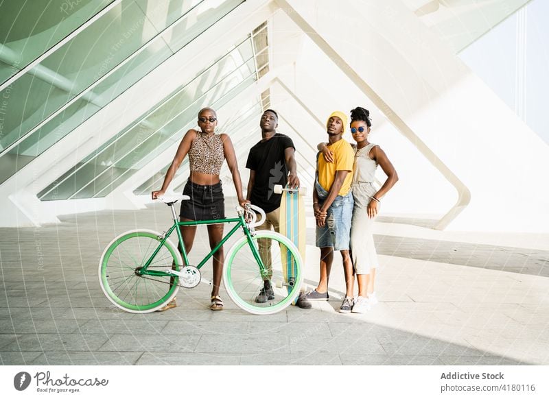 Gesellschaft von fröhlichen Freunden mit Fahrrad und Longboard in der Stadt Unternehmen Hipster Einheit cool Stil Generation Zusammensein ethnisch schwarz