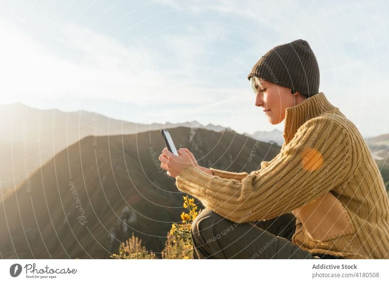 Lächelnde Frau auf Reisen, die in den Bergen auf ihrem Smartphone surft Reisender Berge u. Gebirge Browsen heiter Hochland Surfen Entdecker genießen Ambitus