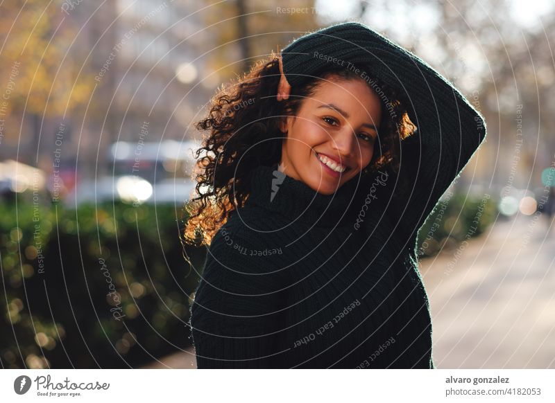 Frau lächelnd beim Posieren im Freien. jung urban Straße Sombrero posierend Stil Großstadt Nahaufnahme lockig Behaarung Frisur Bekleidung trendy eine Pose