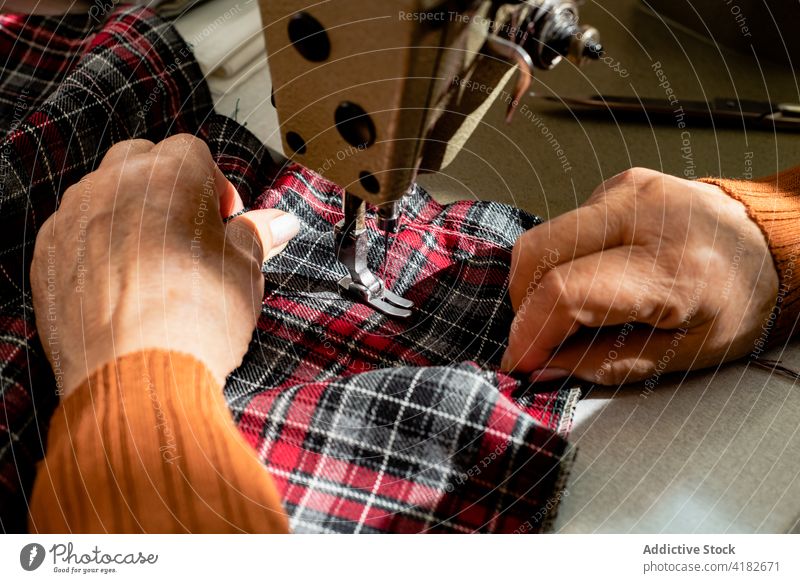 Anonyme ältere Schneiderin beim Nähen von Kleidung in der Werkstatt Frau Näherin nähen Stoff Faser sticken Abwasserkanal Senior Damenschneiderin Handwerkerin