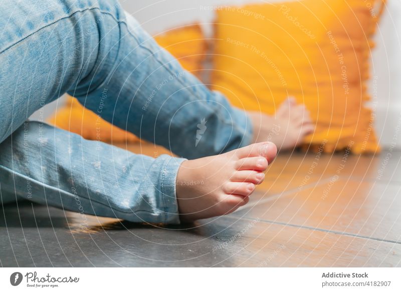 Crop gesichtslose Mädchen in Jeans sitzen auf dem Boden Schwester Bein Stock Jeanshose zu Hause Zusammensein Geschwisterkind Beine gekreuzt Kinder Freund