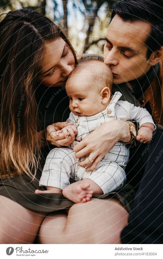 Glückliche Familie mit Baby beim Ausruhen im Park Zusammensein Liebe Eltern Partnerschaft Bonden Pflege Säugling Kind Mutter Vater Elternschaft Kindheit Mama