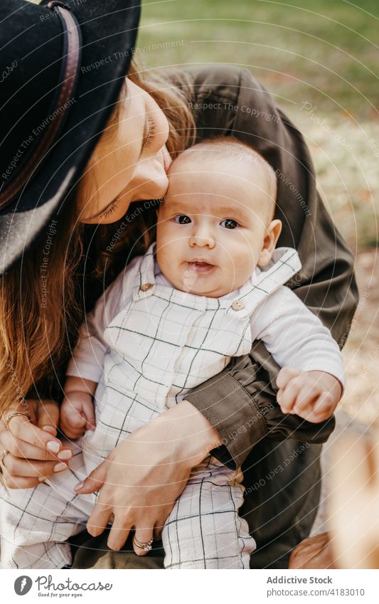 Glückliche Mutter mit Baby genießt die gemeinsame Zeit im Park Liebe Zusammensein Kuss Umarmung Kind Mutterschaft Zuneigung Umarmen Eltern Lifestyle Pflege Mama