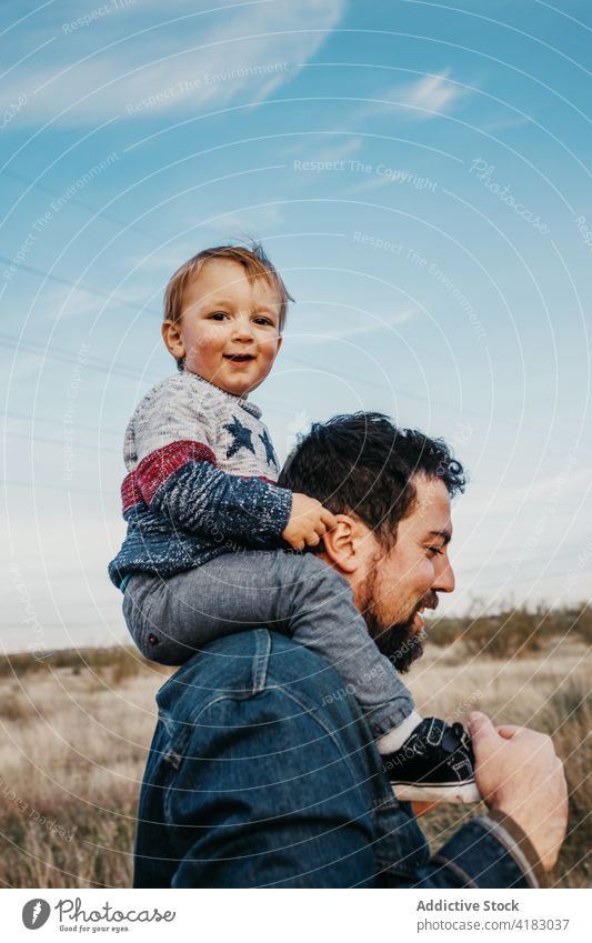 Mann mit süßem Kind auf den Schultern in der Natur Vater Mitfahrgelegenheit heiter Pflege Zusammensein Junge Sohn Landschaft Wochenende Vaterschaft Freude