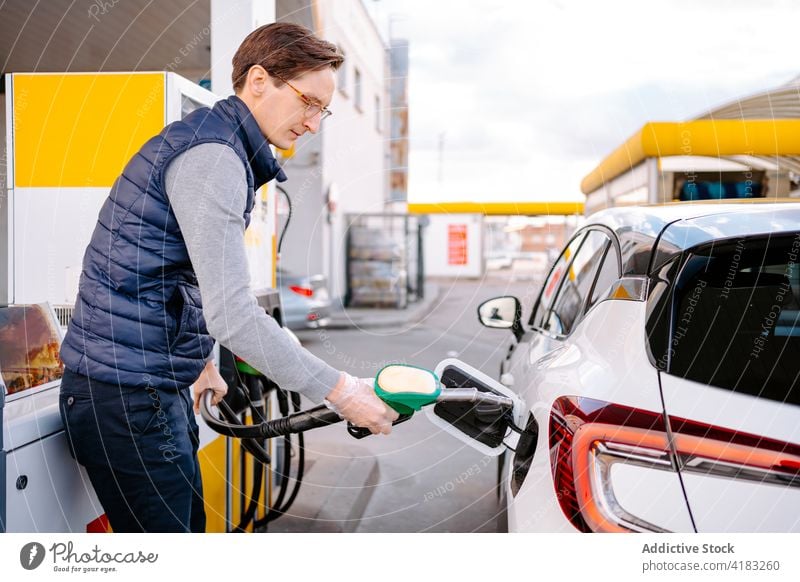 Junger männlicher Fahrer beim Tanken an einer Tankstelle Mann Brennstoff PKW Benzin Station Diesel Fahrzeug ernst Auto Kraft Industrie Tülle jung lässig Brille