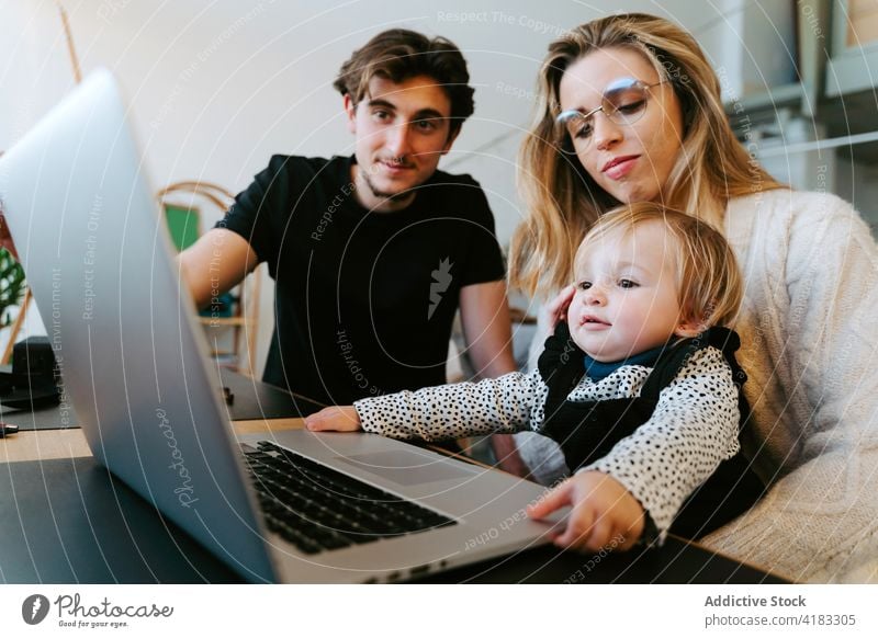 Familie schaut sich zu Hause gemeinsam einen Film auf dem Laptop an zuschauen Kleinkind heimwärts Wochenende Paar wenig Kind Tisch Zusammensein Bonden sitzen