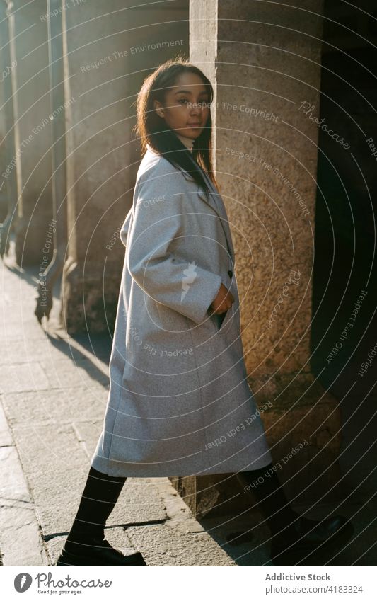 Junge Frau im Mantel auf der Straße Gebäude Stil jung urban Sonnenlicht trendy Herbst ethnisch gealtert Spaziergang Architektur schlendern historisch Lifestyle