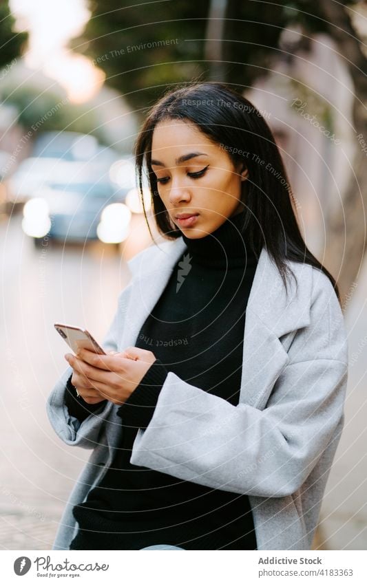 Junge Frau benutzt Smartphone auf der Straße benutzend urban Telefon Mobile Nachricht jung Stil ethnisch Lifestyle Apparatur Gerät Browsen online Internet