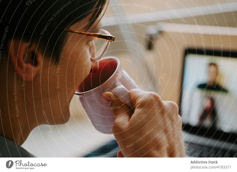 Geschäftsmann führt Videogespräch auf Laptop Videoanruf Tagung Coronavirus Arbeit heimwärts Video-Chat neue Normale trinken Mann männlich online Mitarbeiter