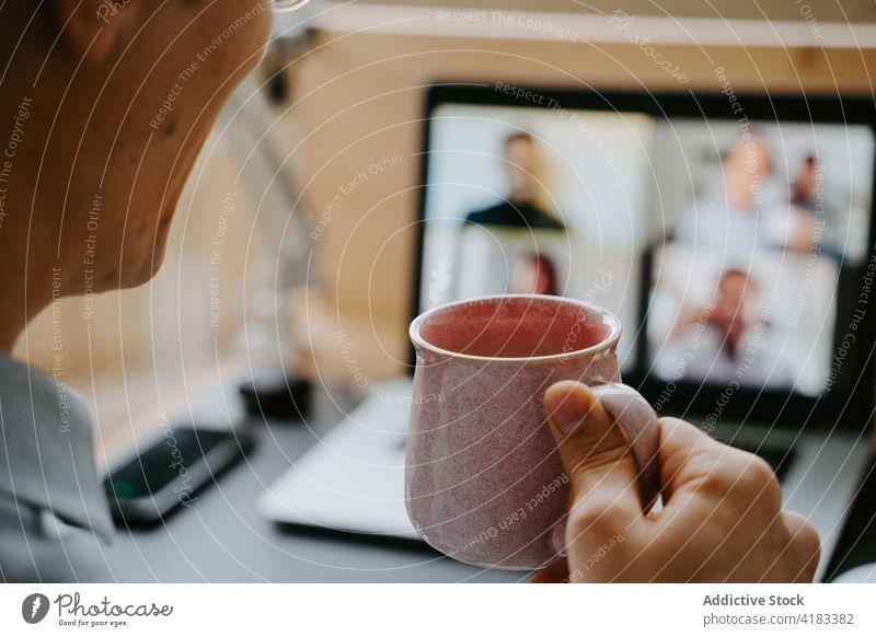 Geschäftsmann führt Videogespräch auf Laptop Videoanruf Tagung Coronavirus Arbeit heimwärts Video-Chat neue Normale trinken Mann männlich online Mitarbeiter