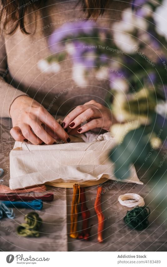 Gesichtslose Frau, die zu Hause mit einem Stickrahmen stickt Stickereien Reifen handgefertigt Faser Fähigkeit Hobby Handarbeit sticken diy Prozess Werkstatt