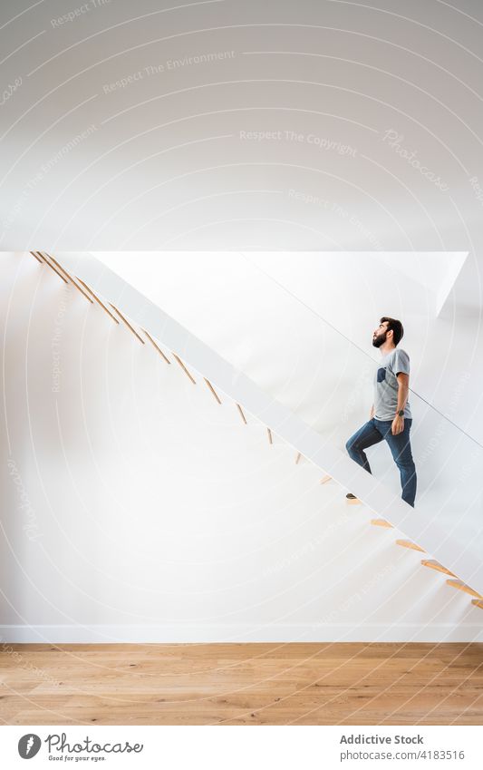 Mann klettert Holztreppe in Haus hoch aufsteigen Treppe Bewegung Architektur Symmetrie Geometrie Minimalismus Schritt Stock Zeitgenosse Stil lässig sehr wenige