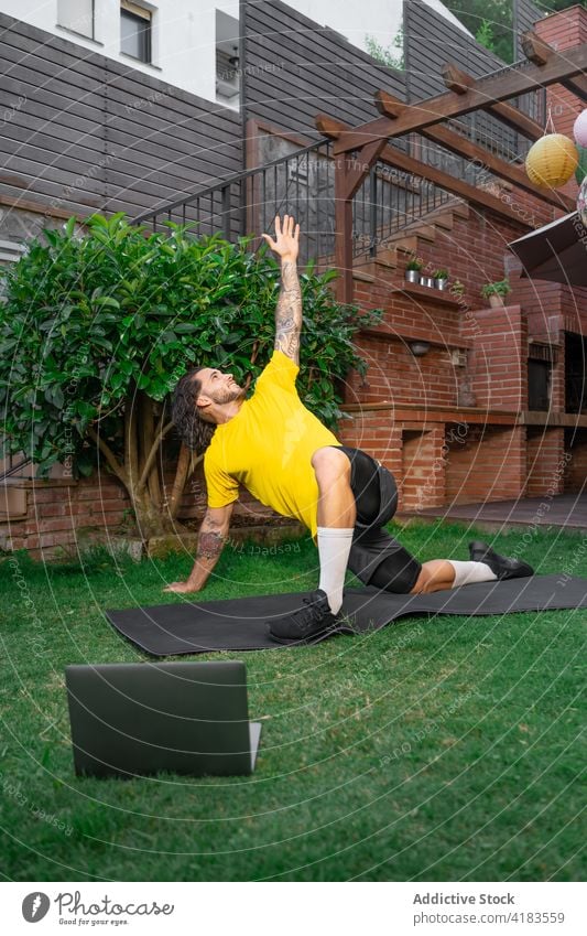 Sportler, der im Garten trainiert und sich das Tutorial auf dem Laptop ansieht Training strecken Schiffsplanken Übung Gleichgewicht Lektion Hof männlich