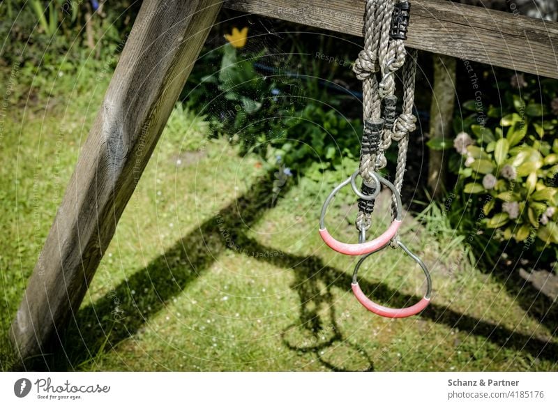 Turnringe hängen an Kinderschaukel im Garten Eigenheim Ringe Schaukel Wiese Rasen Spielplatz eigener Garten Einfamilienhaus spielen Bewegung turnen toben Sommer