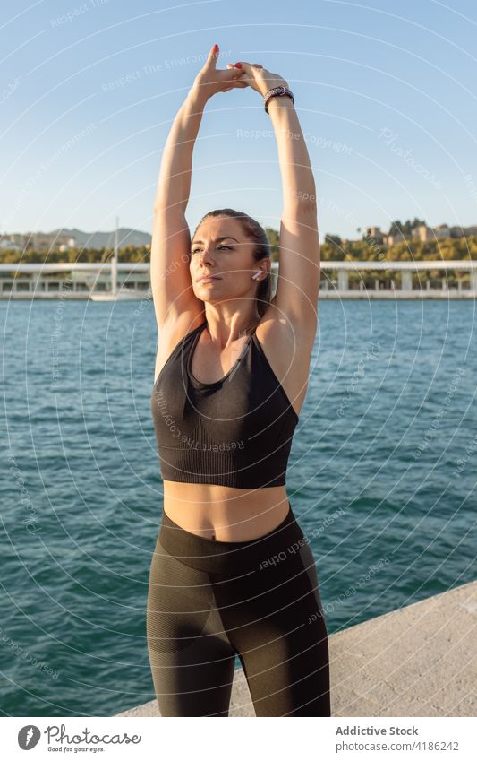 Sportliche Frau beim Training an der Uferböschung Übung Dehnung Stauanlage Fitness Aufwärmen passen Hafengebiet Wellness Gesundheit Wohlbefinden Athlet