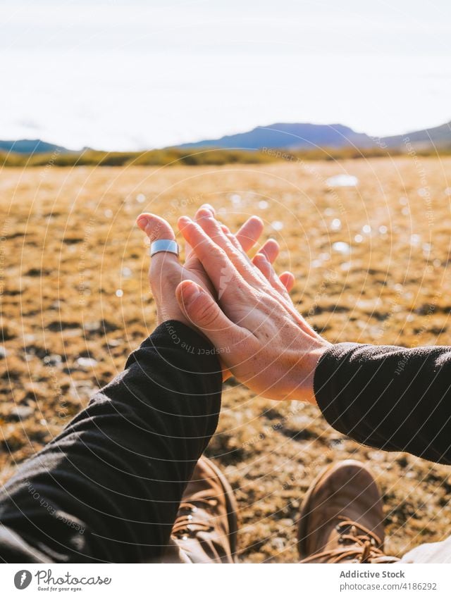 Unbekannter Mann ruht auf grasbewachsenem Boden am Hang im Sonnenlicht reiben Hand ruhen Wiese Wanderer Trekking Tal bewundern Landschaft Natur Fernweh männlich