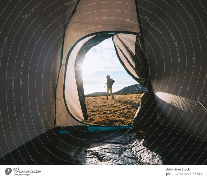 Anonymer Wanderer, der an einem sonnigen Tag in der Nähe seines Zeltes auf dem Campingplatz steht Person Lager Reisender Ausflug Natur Hochland Wanderung