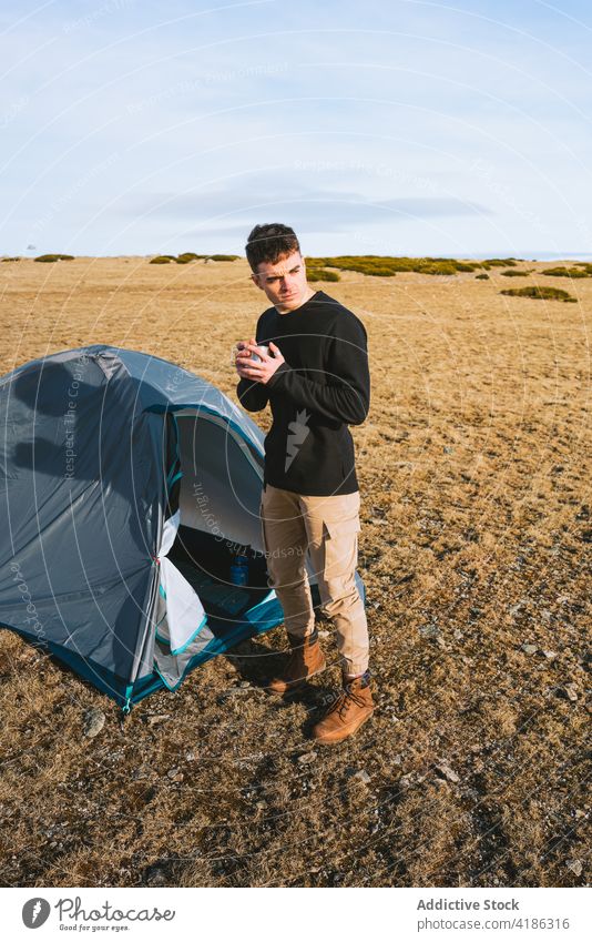 Stilvoller junger Mann genießt ein heißes Getränk beim Camping in den Bergen trinken Zelt Lager Erholung Wanderer Heißgetränk selbstbewusst Natur