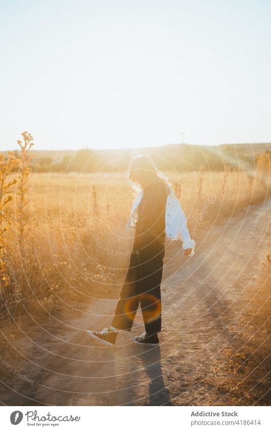 Stilvolle junge Frau tanzt auf dem Lande im Sonnenlicht Tanzen Feld Landschaft Natur sich[Akk] bewegen selbstbewusst aktiv Feiertag Pflanze trendy trocknen Gras