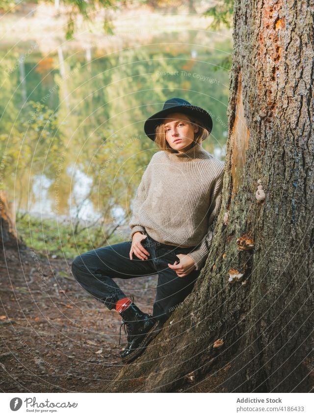 Stilvolle Reisende lehnt an Baum in der Nähe gegen See im Herbst Tourist cool ruhen fettarm Frau Reflexion & Spiegelung Natur anhaben stylisch Ausflug Reisender