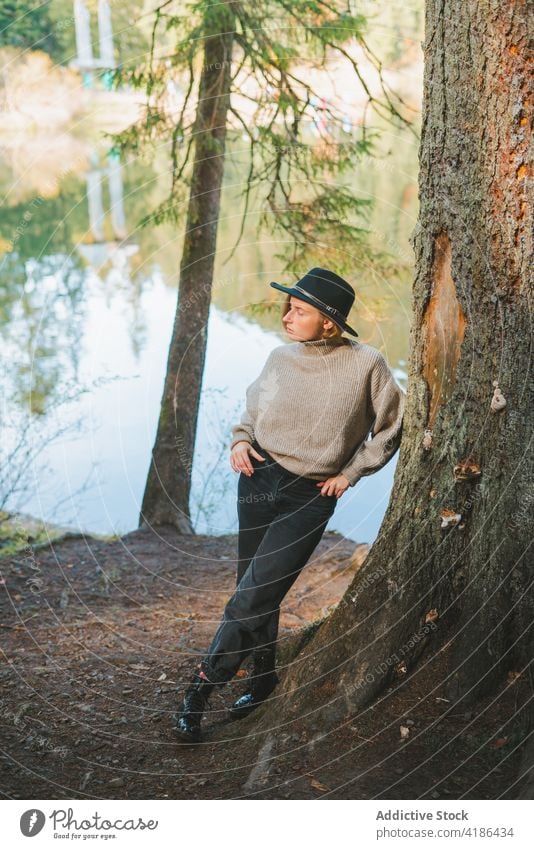 Stilvolle Reisende lehnt an Baum in der Nähe gegen See im Herbst Tourist cool ruhen fettarm Frau Reflexion & Spiegelung Natur anhaben stylisch Ausflug Reisender