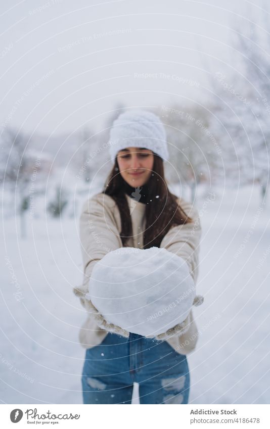 Lächelnde ethnische Frau mit Schneeball in winterlicher Stadt Winter genießen Zeitvertreib Wochenende Park Großstadt Himmel zeigen freie Zeit vegetieren kalt