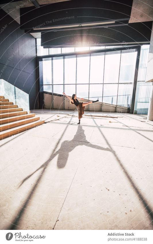 Anonymer Tänzer, der während einer Probe im Gebäude tanzt Künstler Tanzen Choreographie Bein angehoben Arm angehoben ausführen Schatten Theater Frau vorbereiten