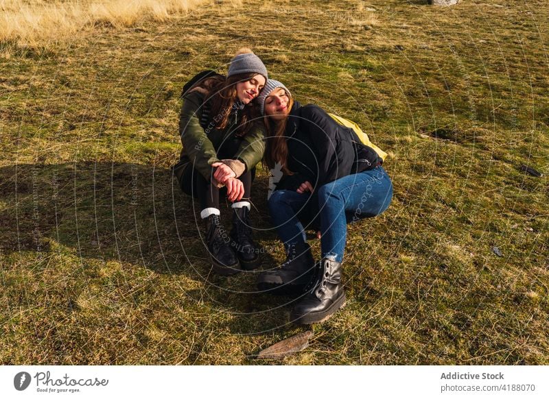 Lächelnde beste Freunde, die sich während eines Ausflugs auf einer Wiese ausruhen Freundin Rasen Freundschaft genießen Augen geschlossen freie Zeit Wochenende