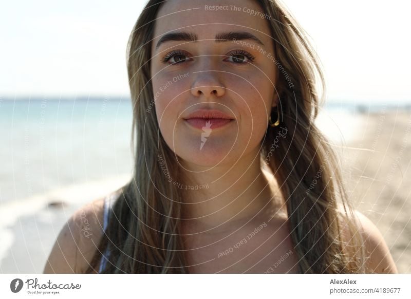 Schönes blondes Mädchen steht am Strand der Ostsee und schaut in die Kamera Lächeln freudig Landschaft Freude Außenaufnahme Gesicht Junge Frau hübsch beschwingt