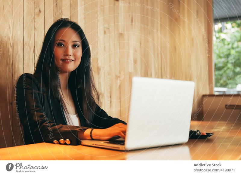 Ethnische Geschäftsfrau isst Sushi und arbeitet am Laptop in einem Café Arbeit essen rollen Projekt Unternehmer abgelegen Frau asiatisch ethnisch Tisch