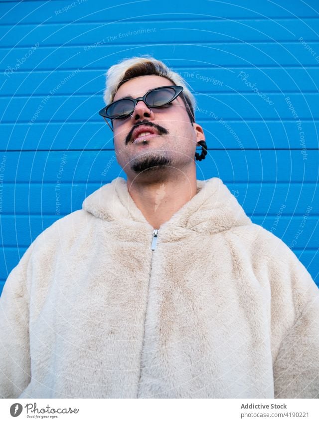 Trendiger Mann mit Sonnenbrille vor blauer Wand Stil cool Outfit Straße trendy lebhaft Farbe männlich Großstadt stehen gutaussehend ausgefallen gefärbtes Haar