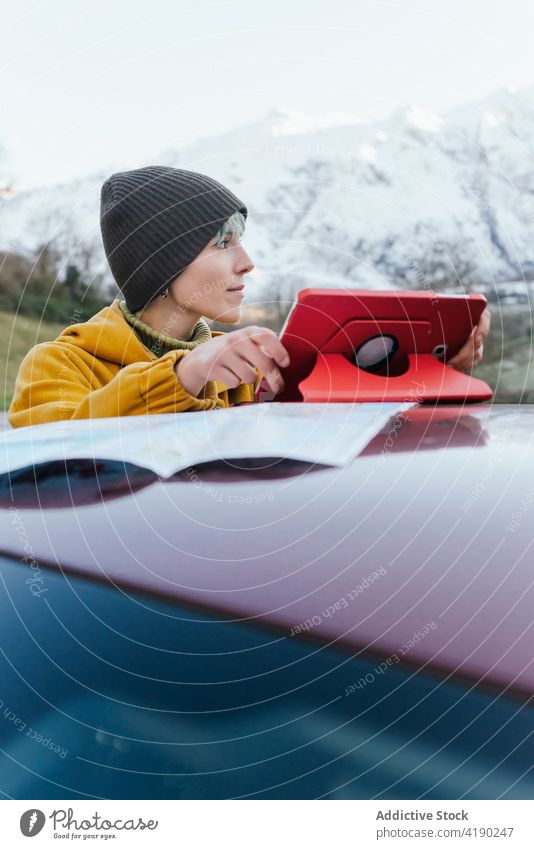 Frau benutzt Tablet in der Nähe des Autos in winterlichem Berggelände PKW Autoreise Landkarte Tablette benutzend Berge u. Gebirge Winter Hochland Inhalt